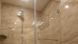 A modern bathroom with a glass-enclosed shower, a toilet, and a marble wall. - acanoa (Calangute)