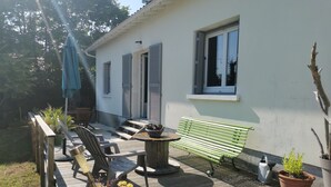 En terrasse med træterrasse, udendørs møbler, en grøn bænk og plantekasser.