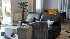 En stue med sofa, lænestol og en potteplante.