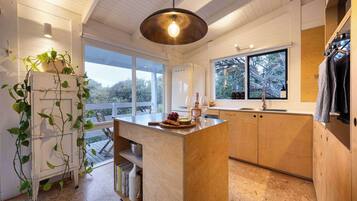 A modern kitchen with a wooden island, large windows, and a hanging light fixture.