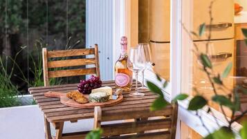 A wooden table with a bottle of rosé wine, two wine glasses, and a wooden board with food items.