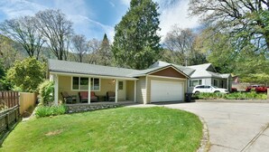 Une maison de plain-pied avec un garage, une véranda abritée avec des chaises et une pelouse bien entretenue.