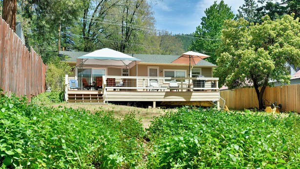 Une maison à deux étages dotée d’une terrasse, d’un patio couvert et d’un grand jardin.