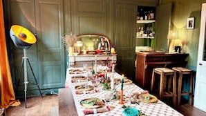Un comedor con una mesa larga dispuesta para una comida, una lámpara de pie y una zona de bar con estantes llenos de botellas.