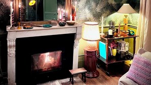 Una sala de estar acogedora con chimenea, un espejo grande y un papel tapiz estampado.