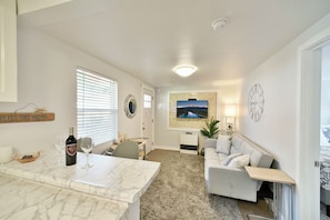 A modern living room with a marble table, a sofa, a TV mounted on the wall, and a fireplace.