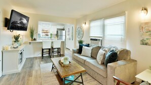 A modern kitchen with a dining area, a sofa, and a TV mounted on the wall. - 4 Homes in downtown Mt. Shasta sleeps 24!! (Mt. Shasta)