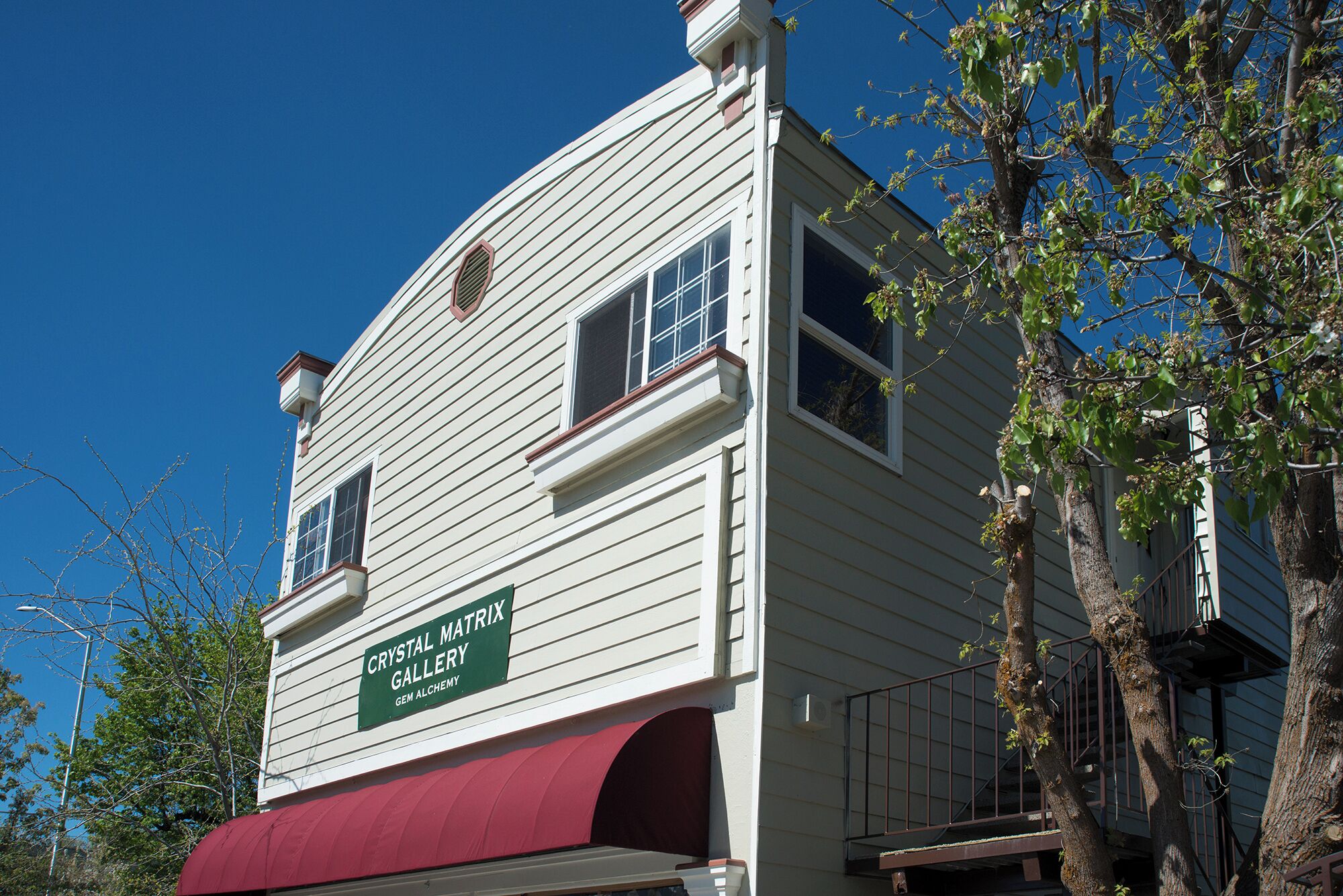 A building with a sign reading "Crystal Matrix Gallery Gem Alchemy."