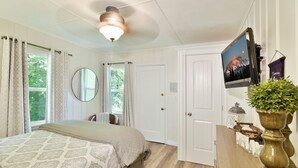 A bedroom with a bed, a ceiling fan, a TV mounted on the wall, and a window with curtains. - 4 Homes in downtown Mt. Shasta sleeps 24!! (Mt. Shasta)