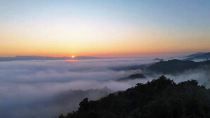 Un lever de soleil sur un paysage montagneux, avec une vue sur le soleil au-dessus des nuages.