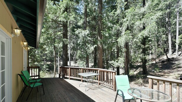 A wooden deck with a glass table and chairs, surrounded by a forest. - Shasta Cottage, A romantic get-away in Mt. Shasta. (Mt. Shasta)