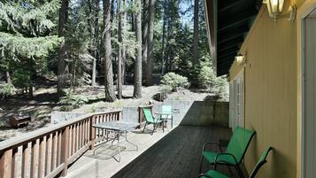 Une terrasse en bois avec une table et des chaises, entourée d’une forêt.