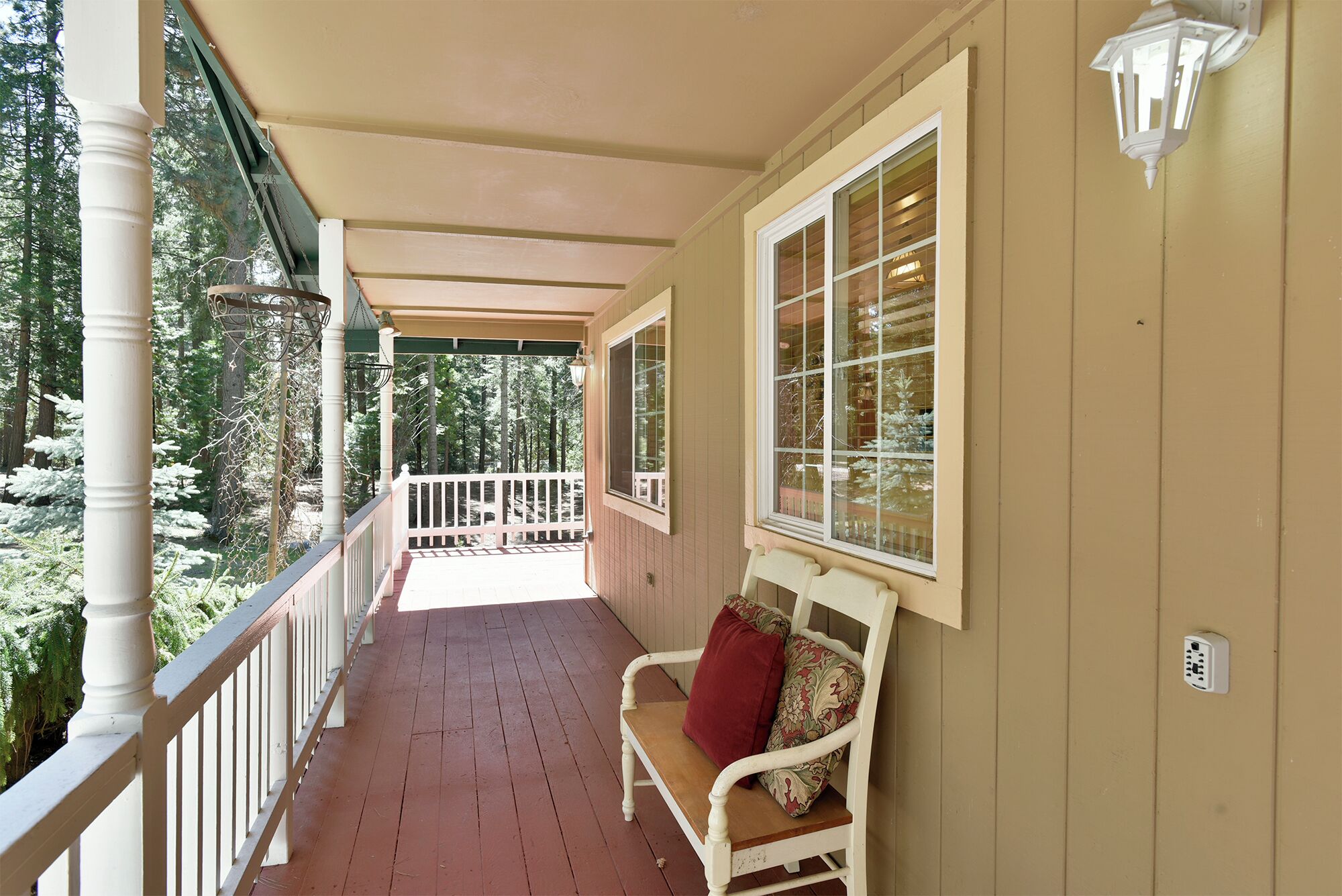 A covered porch with a wooden bench, a railing, and a window with blinds.