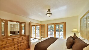 Quarto com cama grande, cômoda de madeira e ventilador de teto.