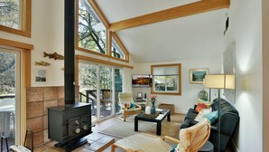 Un salon chaleureux avec une cheminée, des sièges confortables et de grandes fenêtres donnant sur le paysage extérieur.