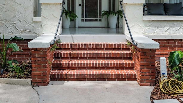 A two-story house with a front porch, a brick staircase, and a mailbox. - Symphony at The Key | 7BR Mansion • 1mi to UF & DT (Gainesville)
