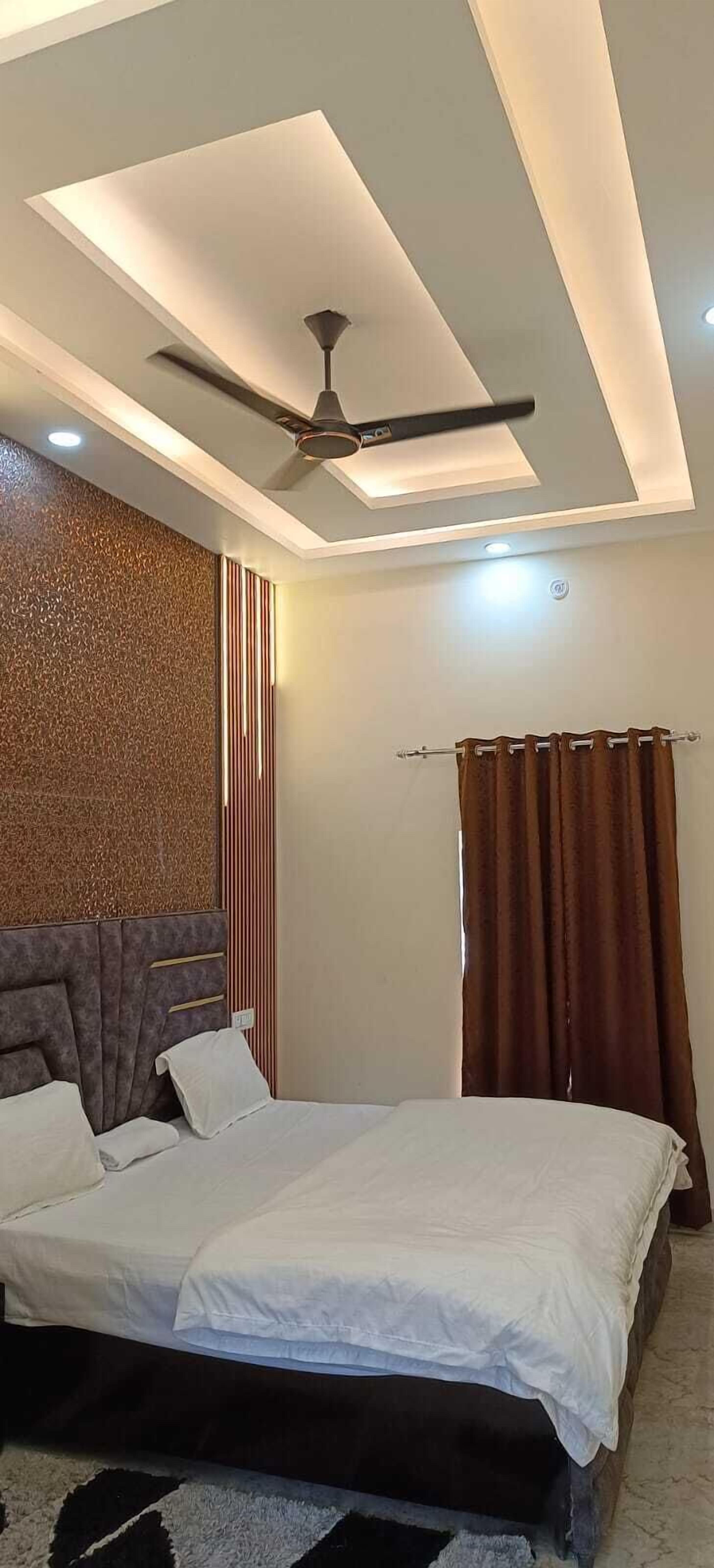 A modern bedroom with a bed, ceiling fan, and a textured wall.