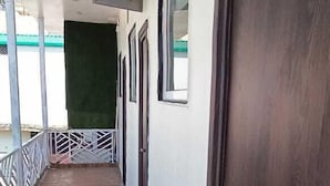 A corridor with a wooden floor, a dark wooden door, and a window on the right. - Hotel The Shivraat (Rishikesh)
