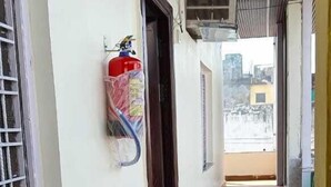 A corridor with a wooden floor, a fire extinguisher mounted on the wall, and a door leading to another room. - Hotel The Shivraat (Rishikesh)