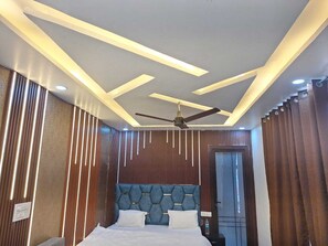 Une chambre d’hôtel moderne, équipée d’un lit, d’un ventilateur de plafond et d’une porte.