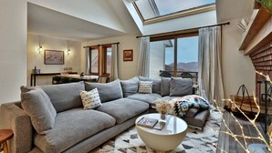 Ein gemütliches Wohnzimmer mit einer Eckcouch, einem runden Couchtisch und einem Essbereich mit Tisch und Stühlen.
