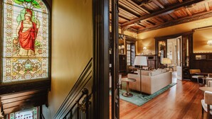 A hotel lobby with a stained glass window, wooden flooring, and a seating area with sofas and tables. - Palacete Severo (Porto)