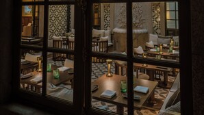 A room with a high ceiling and patterned walls, featuring tables and chairs arranged for dining or socializing. - Palacete Severo (Porto)