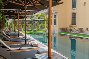 Una piscina al aire libre, sombrillas, tumbonas