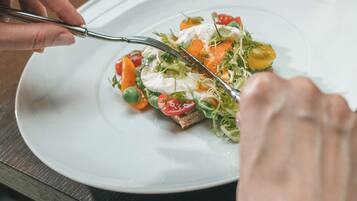 A dining table with a plate of food, a fork, and a knife.