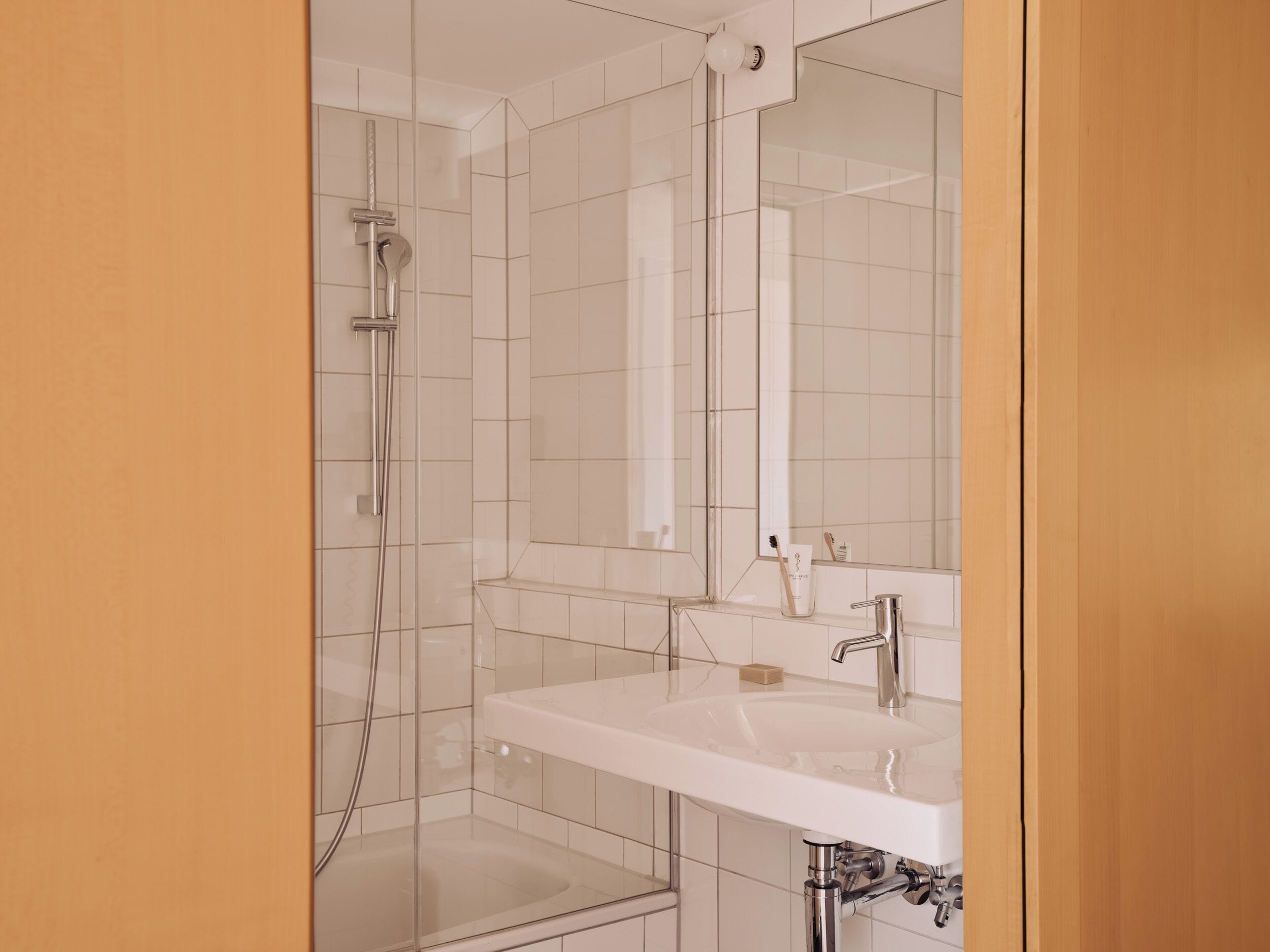 A modern bathroom with a glass shower enclosure, a white sink, and a large mirror.