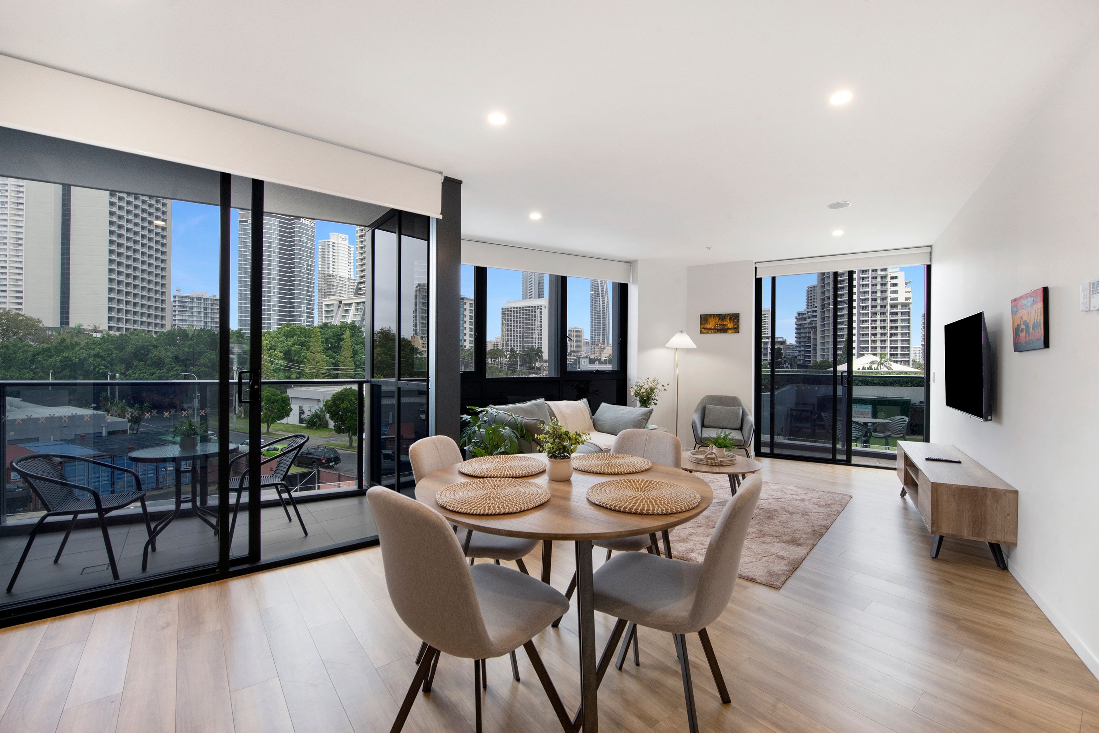 Una sala de estar moderna con comedor, ventanas amplias y vista a la ciudad.