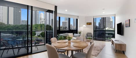 Una sala de estar moderna con comedor, ventanas amplias y vista a la ciudad.