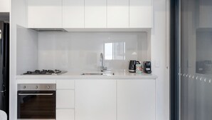 A modern kitchen with white cabinetry, a stainless steel stove, and a sink.