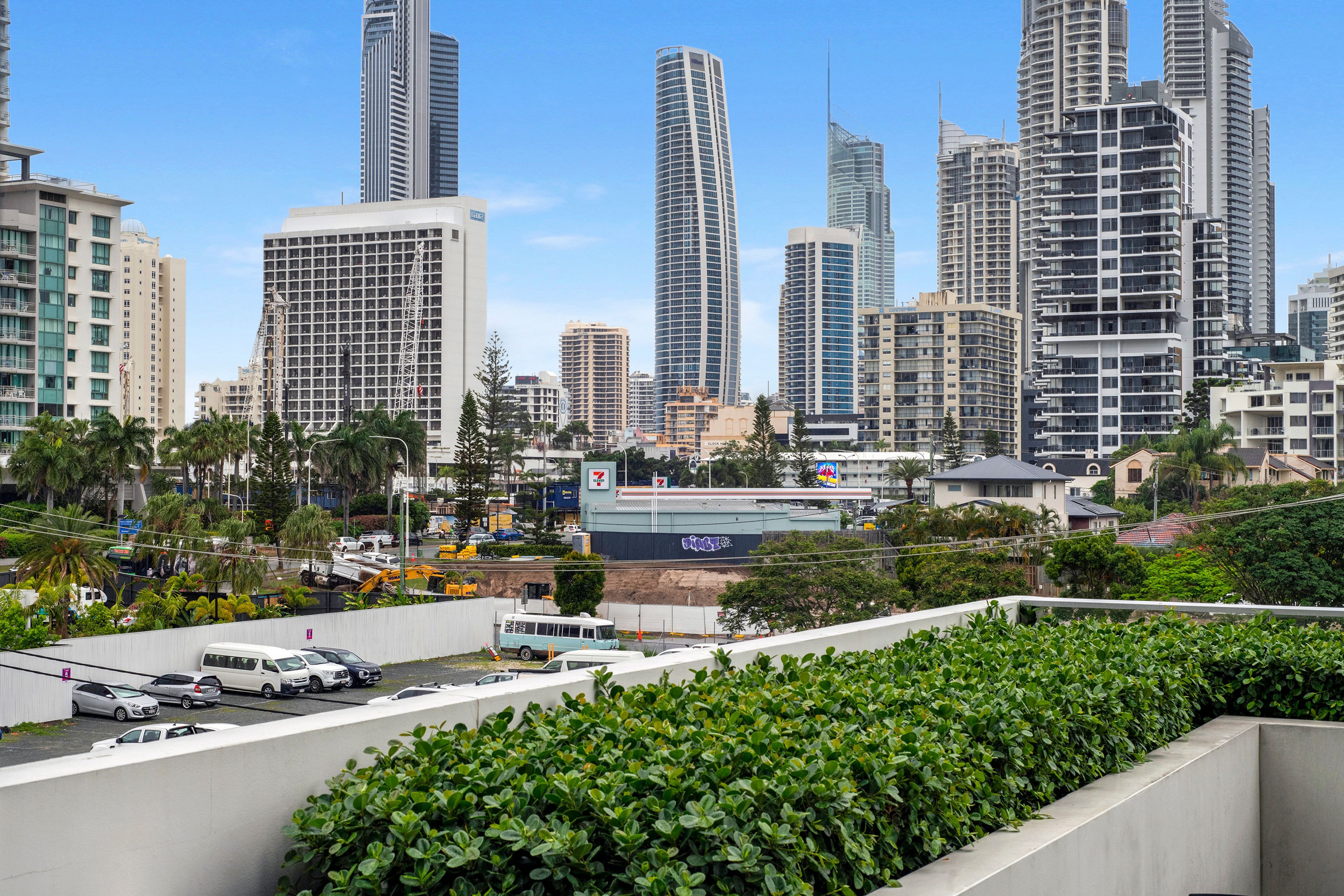 Un paisaje urbano con edificios altos, un estacionamiento y zonas verdes.