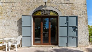 Ein Steinhaus mit Glastür und zwei grauen Metallrollos.