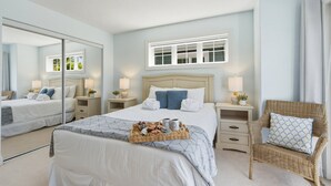 Une chambre à coucher avec un grand lit, une chaise, une table de chevet, un miroir et une fenêtre.