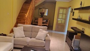 A living room with a sofa, a coffee table, and a staircase leading to a dining area. - NOAH'S ARK (Valle de Oro)