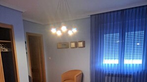A bedroom with a bed, a chair, a wardrobe, and a bedside table with a lamp. - NOAH'S ARK (Valle de Oro)