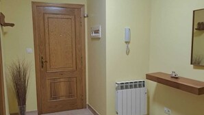 A room with a wooden door, a radiator, a telephone, and a shelf with a vase. - NOAH'S ARK (Valle de Oro)