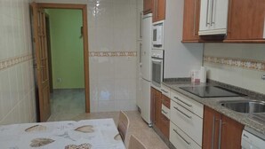 A kitchen with a dining table, cabinets, and a refrigerator. - NOAH'S ARK (Valle de Oro)