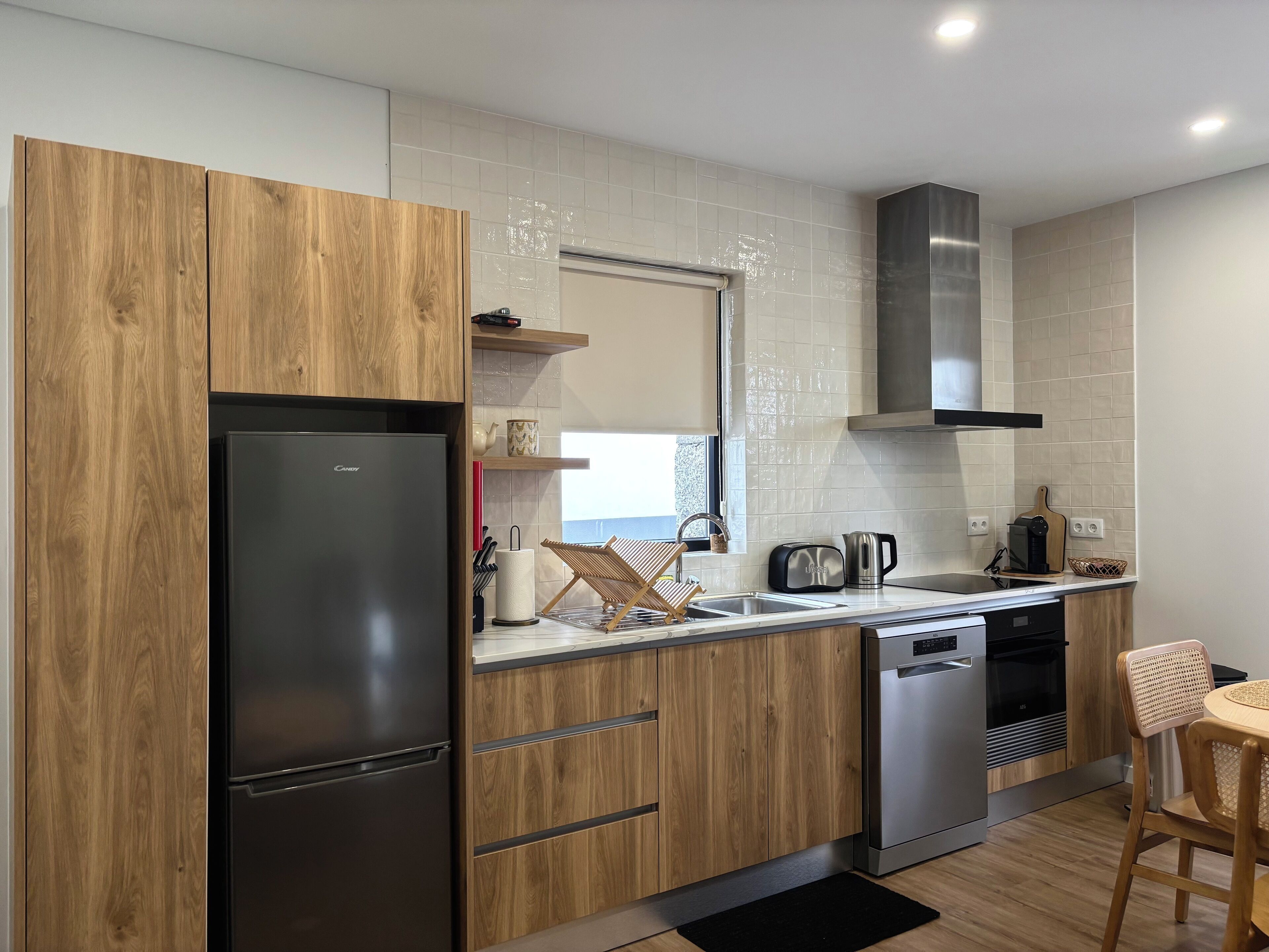 Une cuisine moderne avec des meubles en bois, un réfrigérateur en acier inoxydable, un lave-vaisselle et une fenêtre offrant une belle vue.
