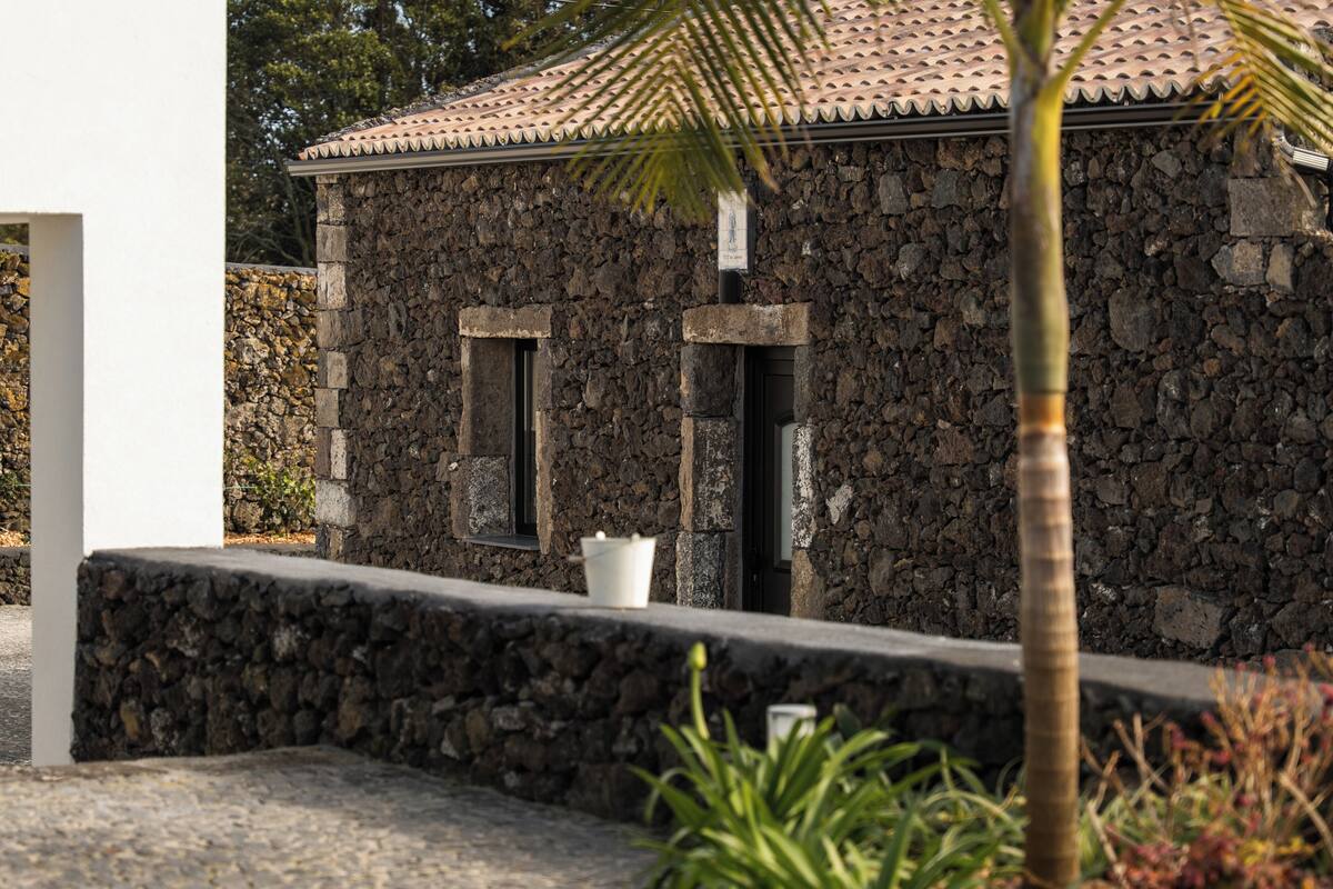A stone building with a tiled roof, a small window, and a white planter box.