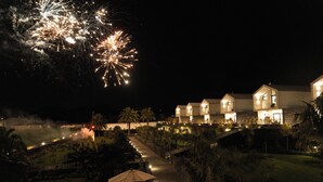 A nighttime view of a resort with multiple buildings, a well-lit pathway, and outdoor seating areas. - Azores Homes Resort & Spa (Ponta Delgada)