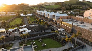 A resort with a pool, outdoor seating, and a view of the surrounding landscape. - Azores Homes Resort & Spa (Ponta Delgada)
