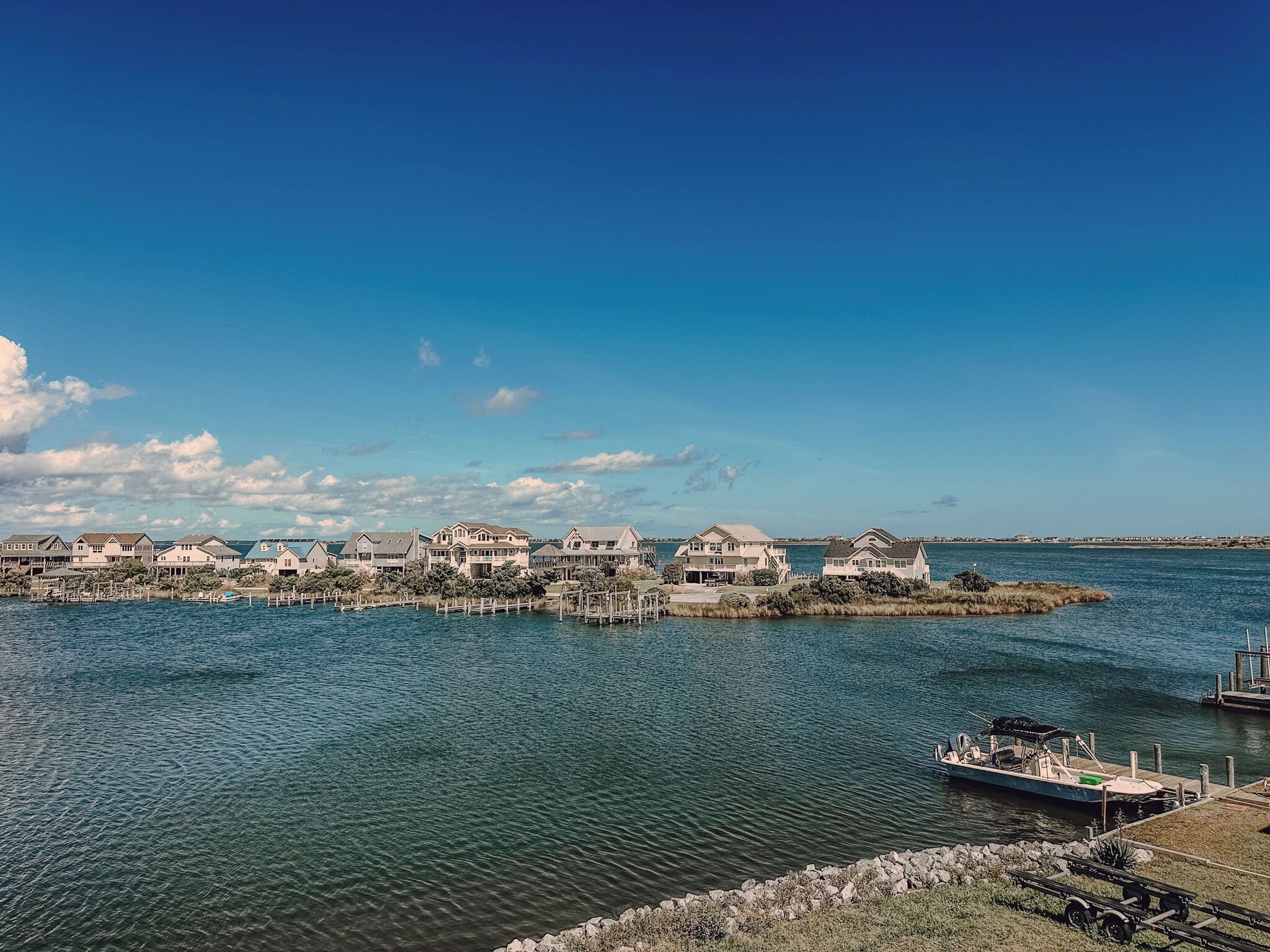 A waterfront property with multiple houses connected by docks, a boat docked at the pier, and a clear view of the water.