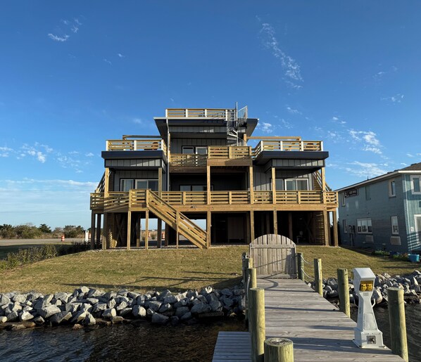 A multi-story wooden building with a wooden deck leading to a gated entrance.