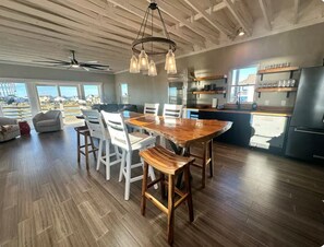 A spacious kitchen with a wooden dining table, white chairs, and a built-in oven.