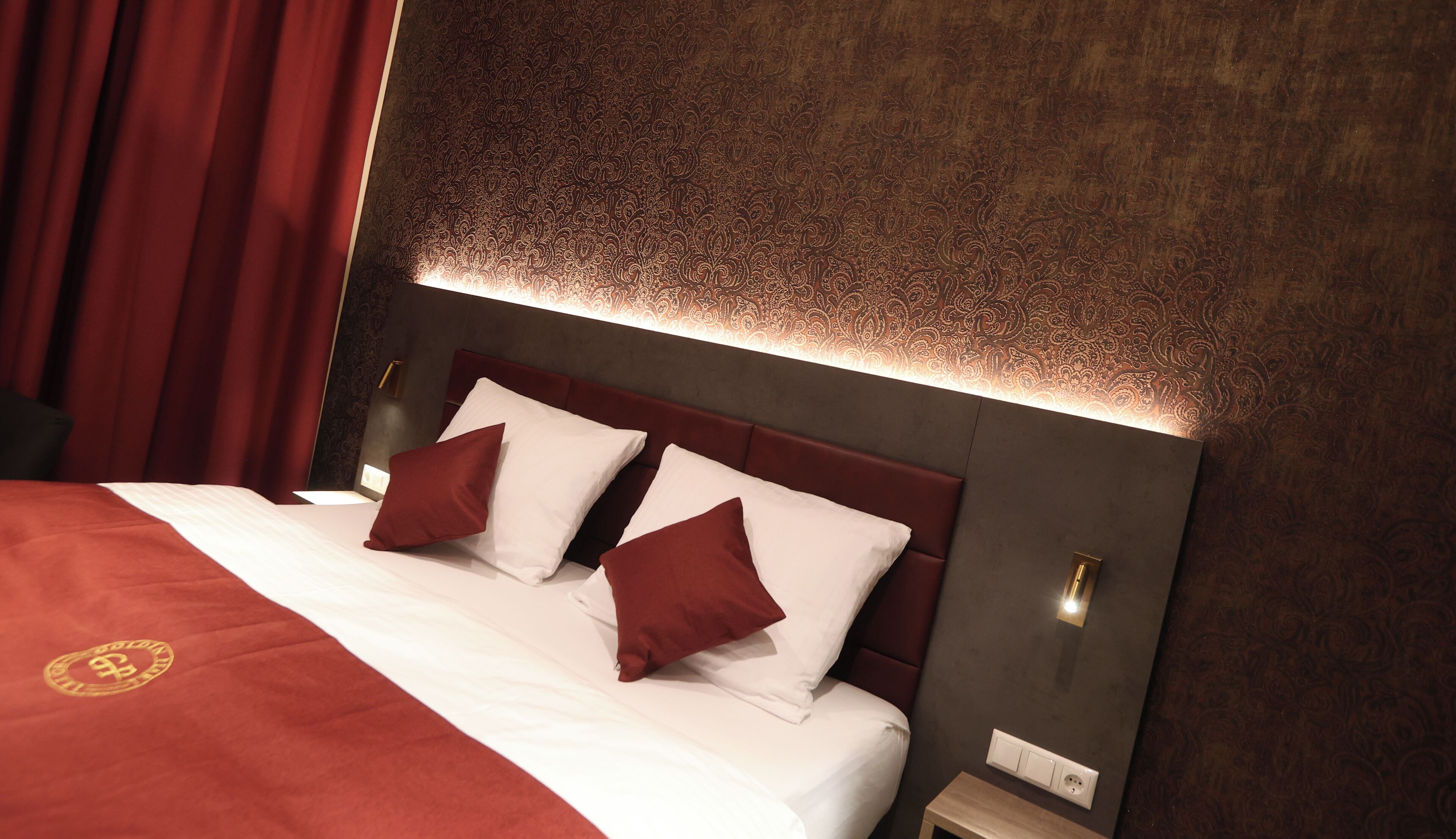 Ein Hotelzimmer mit einem großen Bett, roten Vorhängen und einer Wand mit Muster.
