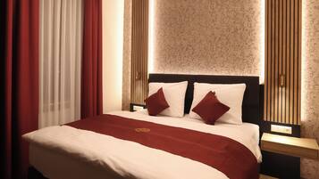 A neatly made bed with a red and white bedspread, two red pillows, and a wooden headboard.
