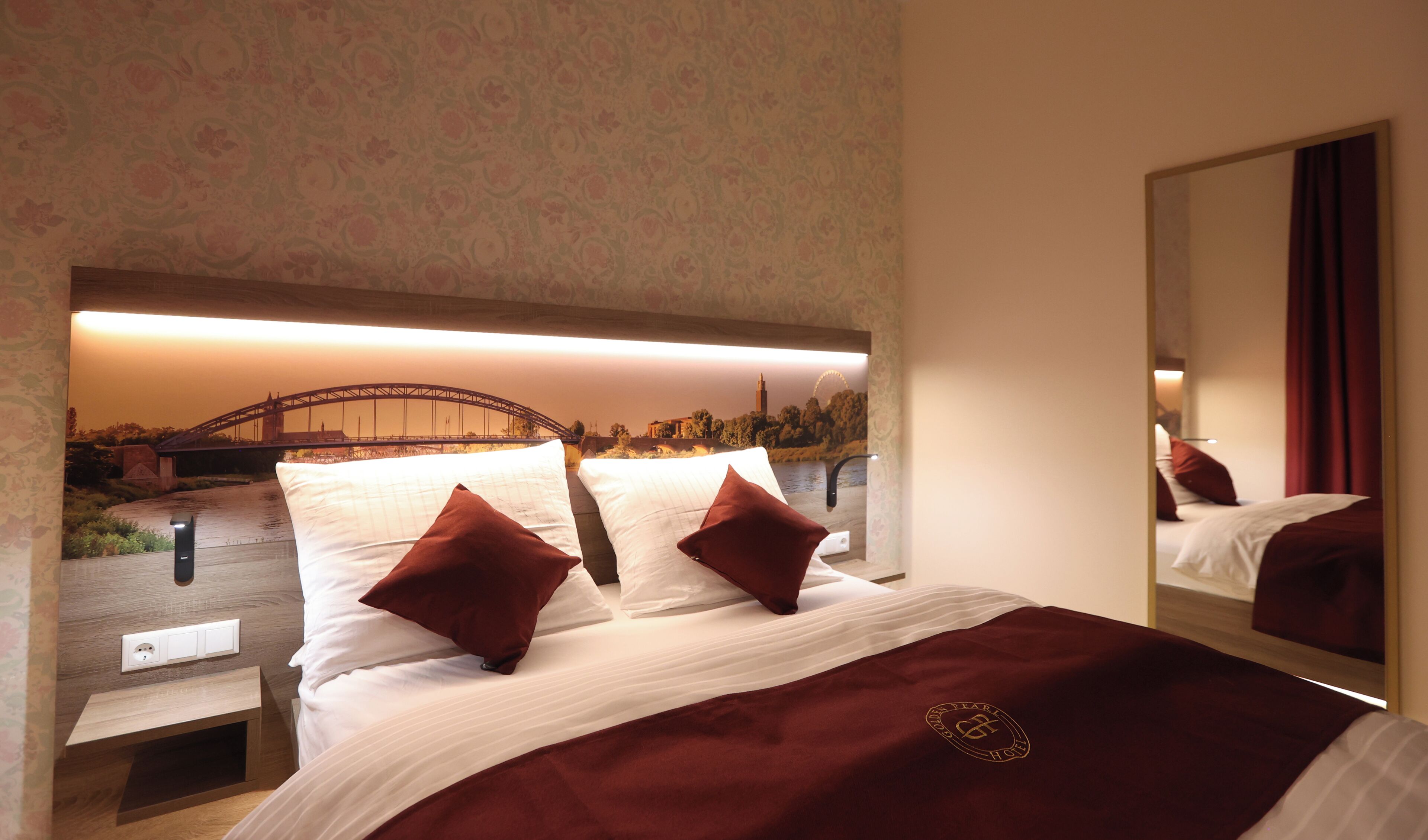 A hotel room with a bed, a mirror, and a view of a bridge.